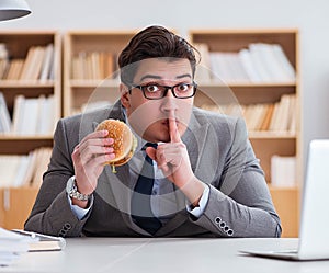 Hungry funny businessman eating junk food sandwich