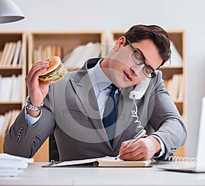 Hungry funny businessman eating junk food sandwich