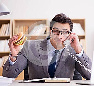 Hungry funny businessman eating junk food sandwich