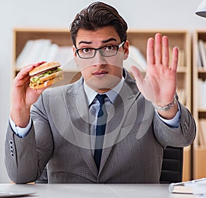 Hungry funny businessman eating junk food sandwich