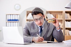 The hungry funny businessman eating junk food sandwich