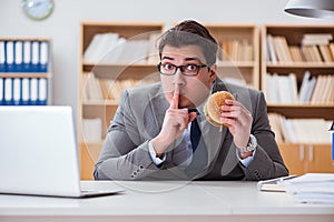 The hungry funny businessman eating junk food sandwich