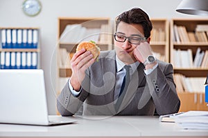 The hungry funny businessman eating junk food sandwich