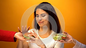 Hungry girl choosing hamburger instead of salad, cheap junk food vs healthy diet