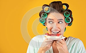 Hungry Girl With Curlers Eating Cake Posing On Yellow Background