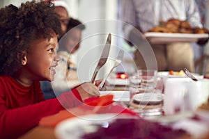 Hungry Girl Waiting For Food As Multi Generation Family Sit Down To Eat Christmas Meal At Home