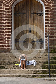 A Hungry Homeless Abandoned Runaway Child Looks For Food And Shelter In Front Of A Church