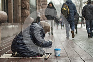 Hungry homeless beggar woman beg for money on the urban street in the city from people walking by