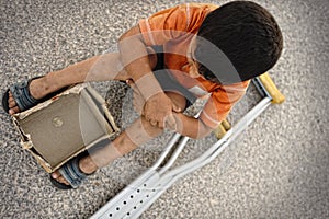 Hungry kid begging with a crutches beside