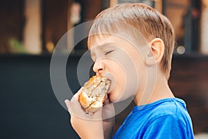 Hungry kid eating a burger at outdoors cafe