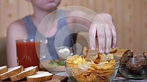 Hungry Kid Hand Takes Crispy Golden Potato Chips from Plate. Junk Food in Dinner