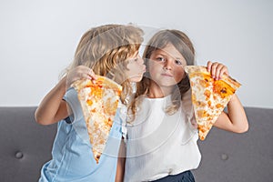 Hungry kids eating pizza. Happy children eating pizza and having fun together. Happy kids holding pizza slice near face