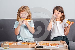 Hungry kids eating pizza. Two young children bite pizza indoors.