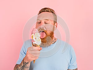 Hungry man with beard and tattoos eats a big icecream