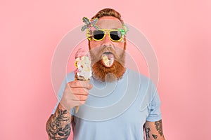 Hungry man with beard and tattoos eats a big icecream