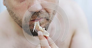 A hungry man. Close-up of a naked male with a beard eating.