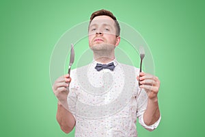 Hungry man holding fork and knife on hand to eat