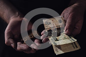 Hungry man holding money and bread on a black background, hands wn