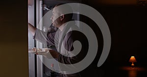 Hungry man looking in a fridge taking plate with food at night funny behaving shot on red epic