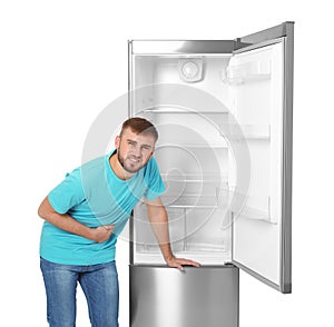 Hungry man near empty refrigerator on white background