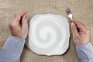 Hungry man waiting for his meal over empty plate