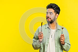 Hungry man waiting for serving dinner meal dishes with restlessness holding cutlery fork knife