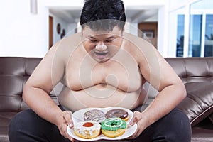 Hungry overweight man holding donuts