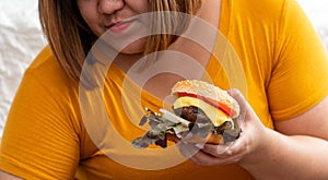 Hungry overweight young asian woman holding hamburger, Her hungry all time and overeat, gluttony and binge eating. Her lifestyle