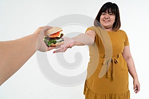 Hungry overweight young Asian woman holding hamburger on isolated background, Her hungry all time and overeat, gluttony and binge