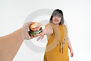 Hungry overweight young Asian woman holding hamburger on isolated background, Her hungry all time and overeat, gluttony and binge