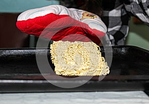 A hungry person about to cook instant noodles on a baking sheet in the oven