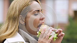 Hungry pregnant lady eating meat burger, having healthy appetite, lunchtime