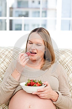 Hungry pregnant woman eating strawberries-