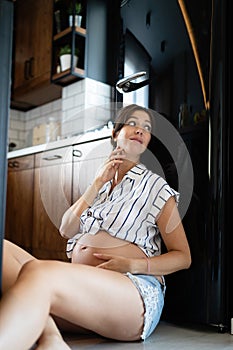 Hungry pregnant woman looking for food in the fridge