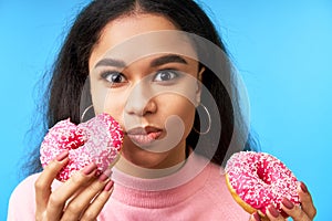 Hungry pretty girl eating donuts isolated over blue background