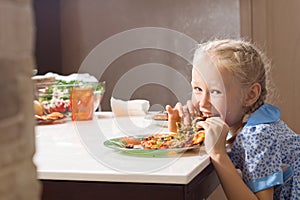 Hungry pretty little girl devouring homemade pizza
