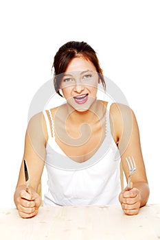 Hungry screaming girl holding fork and knife.