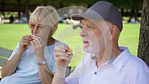 Hungry seniors eating sandwiches in park. Tourist having lunch in public park enjoying summer sunny day