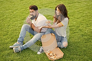 Hungry students sharing food. Pure enjoyment. Couple eating pizza relaxing on green lawn. Fast food delivery. Bearded