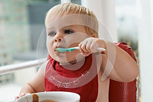 Hungry, sweet and baby eating porridge for health, nutrition or child development at home. Food, cute and girl toddler