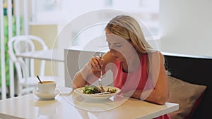 Hungry woman eating salad for lunch at restaurant