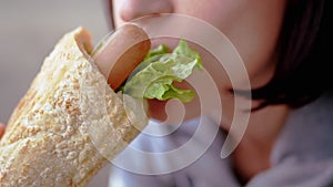 Hungry Woman Eats Appetizing Juicy American Hot Dog with Sausages in a Diner