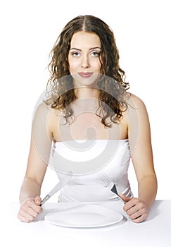 Hungry woman seating at table with empty plate