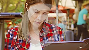 Hungry woman sitting in cafe looking at menu. Smiling beautiful female choosing food at restaurant