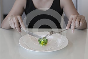 A hungry woman on a weight loss diet. Empty plate with a vegetable. Low calorie diet