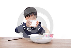 Hungry yellow-skinned little girl is gulping soup photo