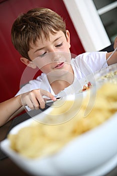 Hungry young boy eating grilled food