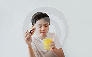 Hungry young boy eating homemade bacon sandwiches with mixed vegetables, Healthy Kid drinking juice for breakfast at home, Child