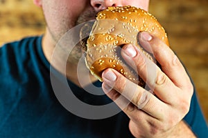 The hungry young man aggressively eats a burger. Fast food