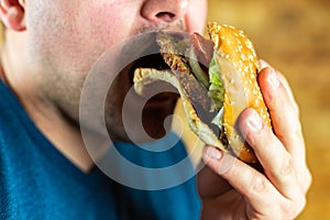 The hungry young man aggressively eats a burger. Fast food